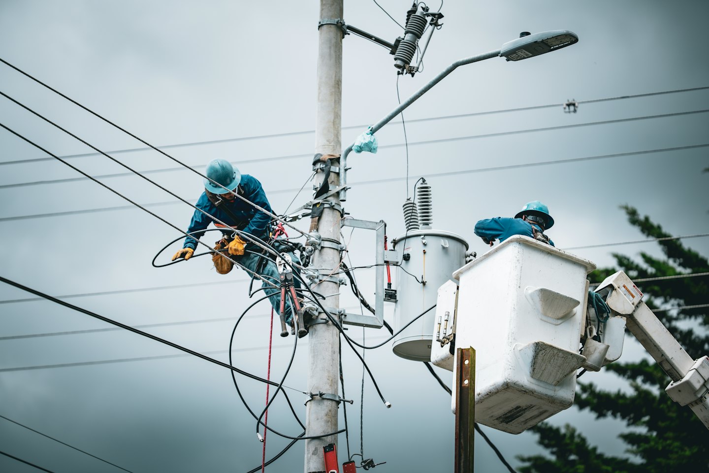 Utility workers on a power pole with transformer.