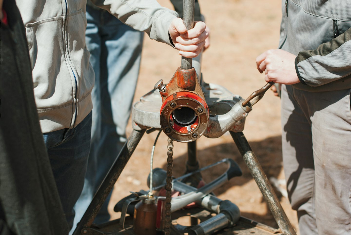People working together using a pipe threading machine.