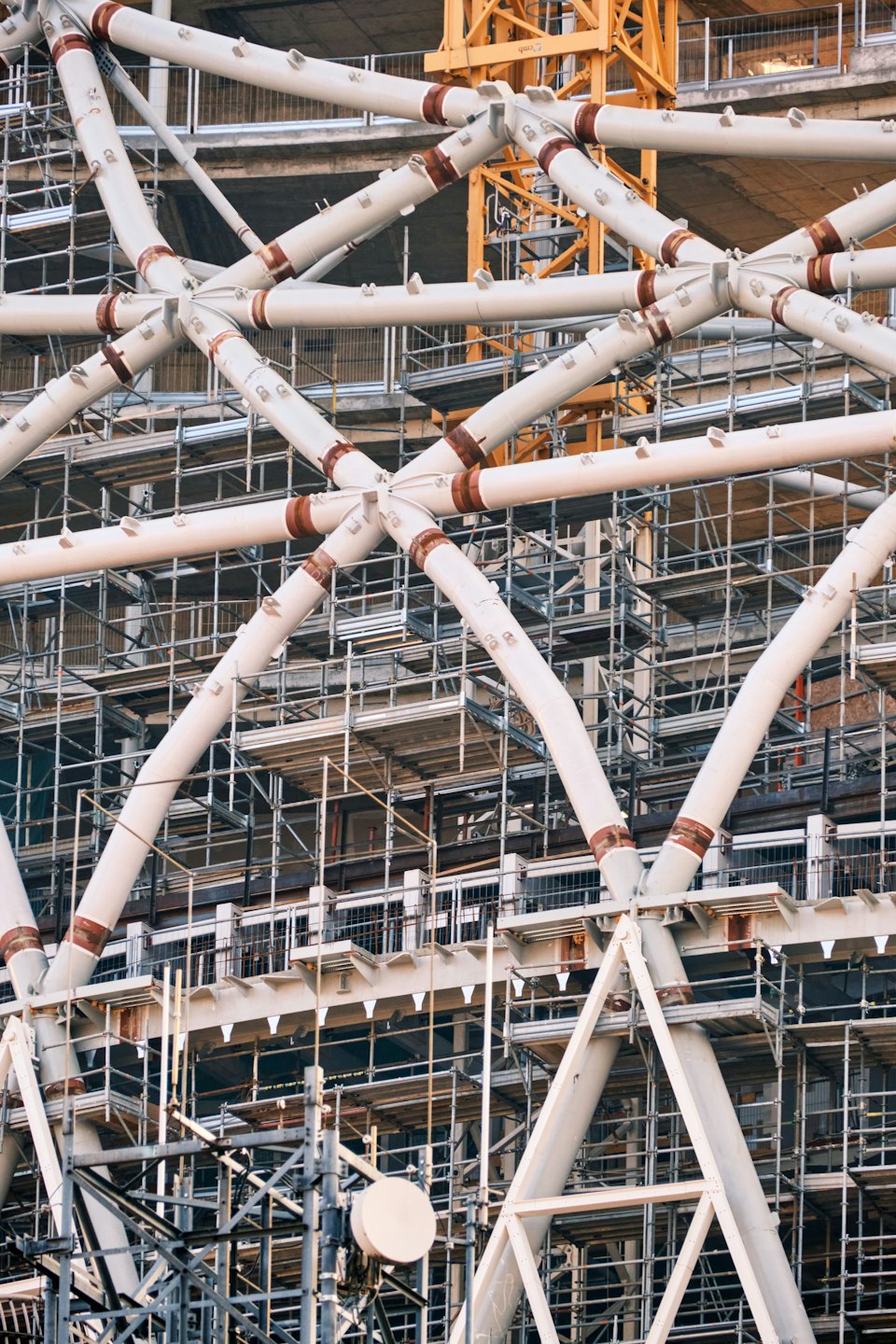 White steel pipes and a yellow crane at a construction site.