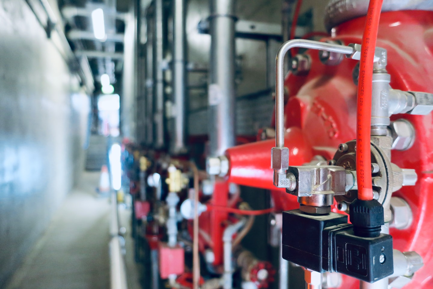 Red industrial pipes and control systems in a utility space.